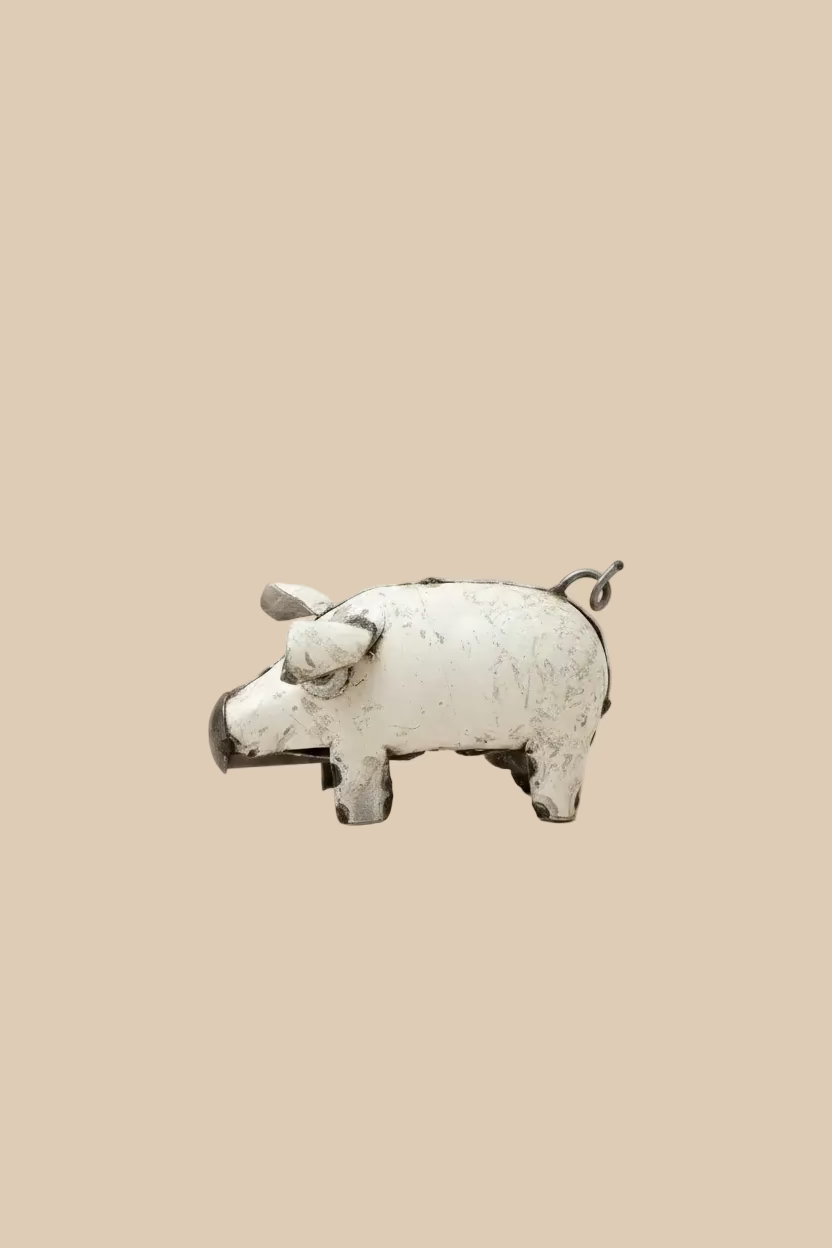 Small white recycled-metal pig sculpture against a beige background.