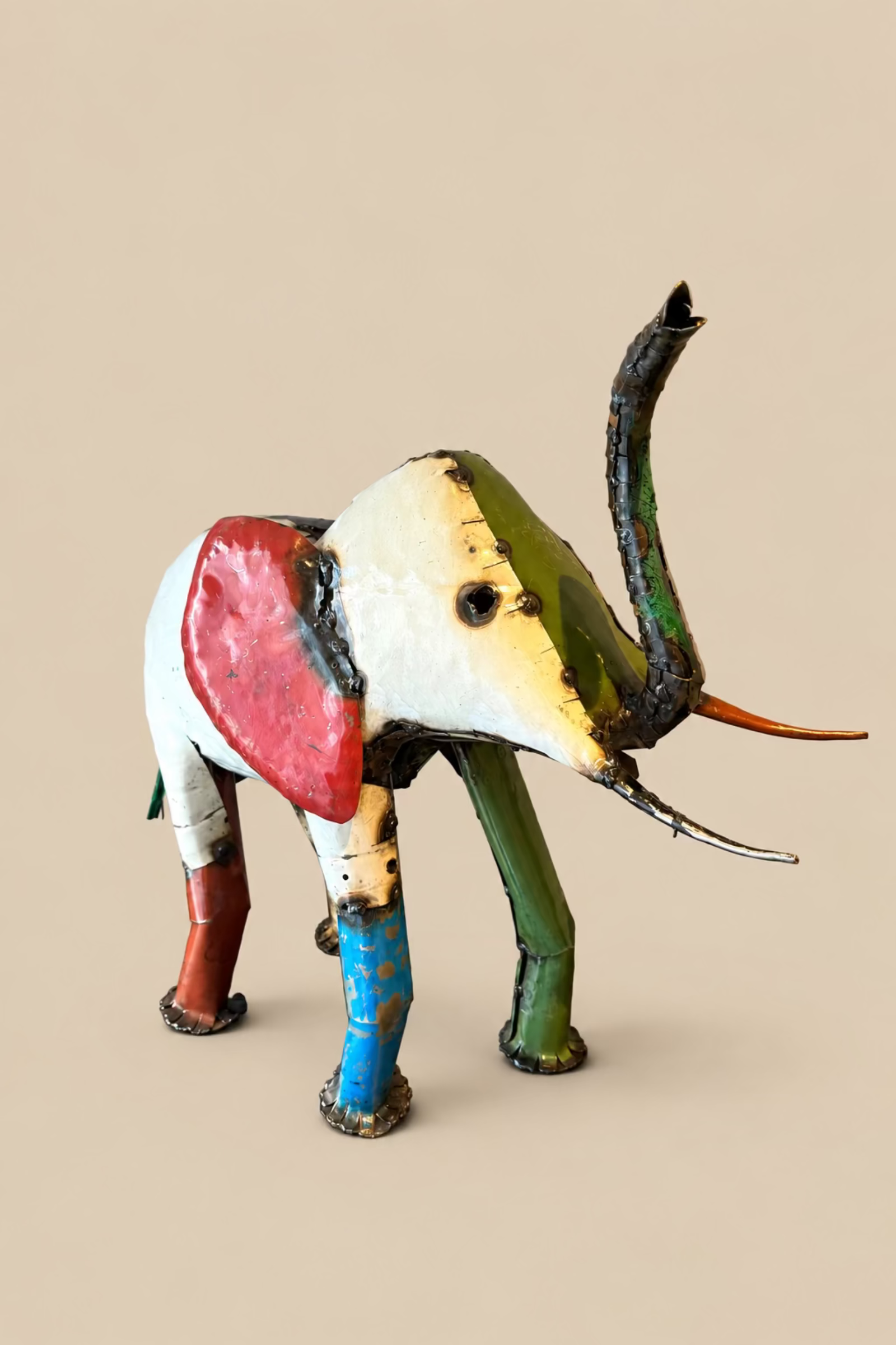 Large Elephant with a red body and cream-and-yellow ear, side view.