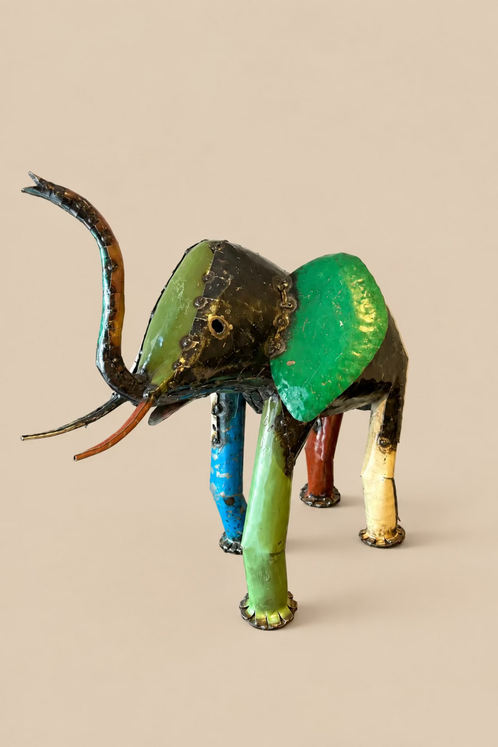 Large Elephant with green, yellow and dark metal panels, viewed at an angle.