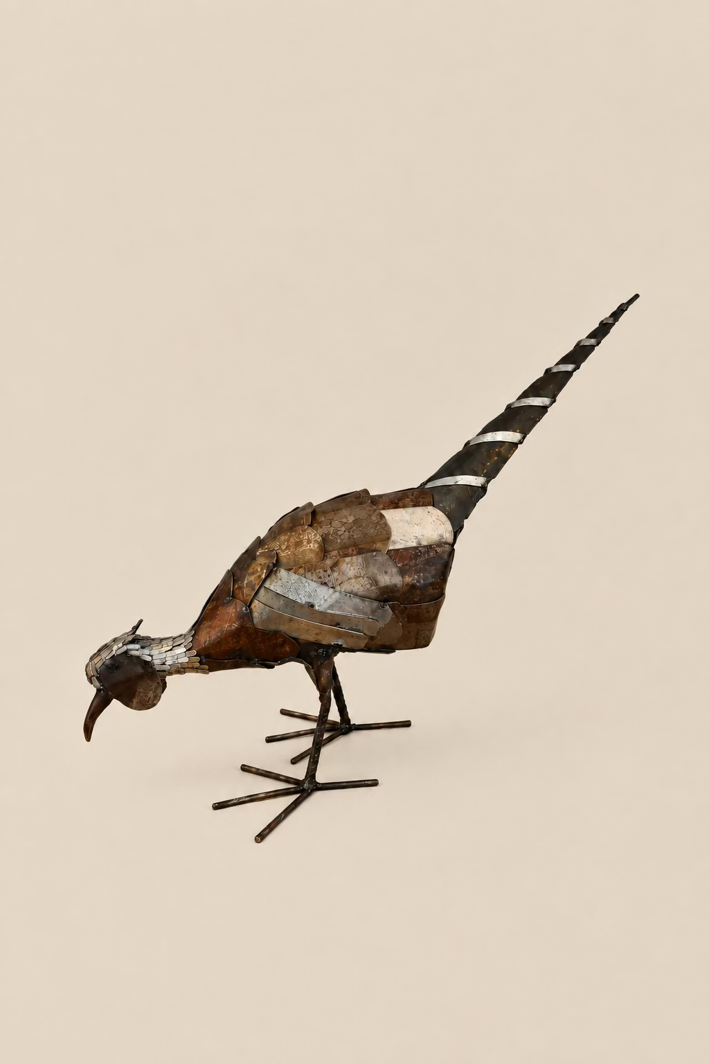 Foraging Pheasant metal sculpture with its head lowered, layered bronze-toned body and long banded tail.