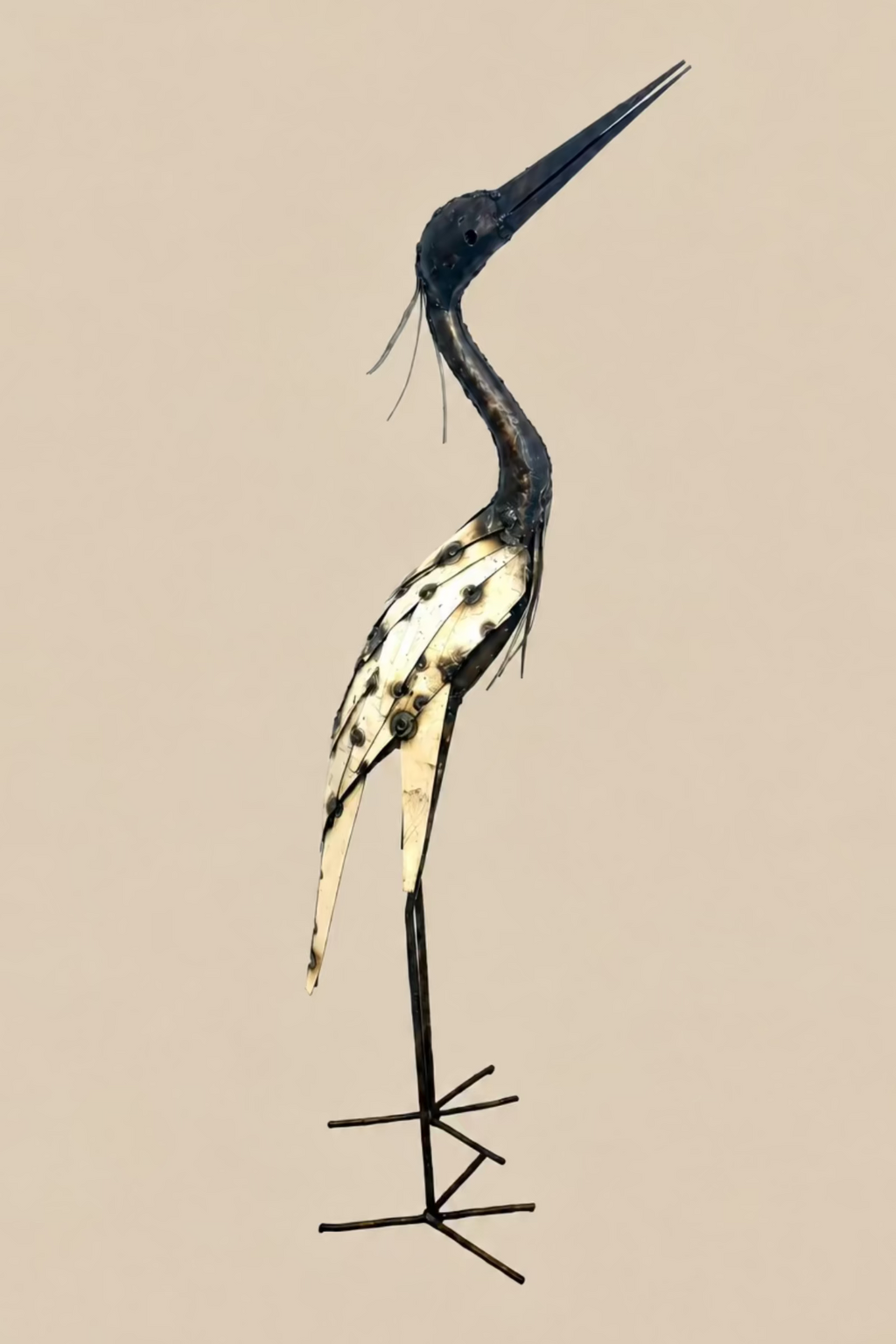 Large Heron metal sculpture with a long dark neck, cream wing panels and slender legs, side view.