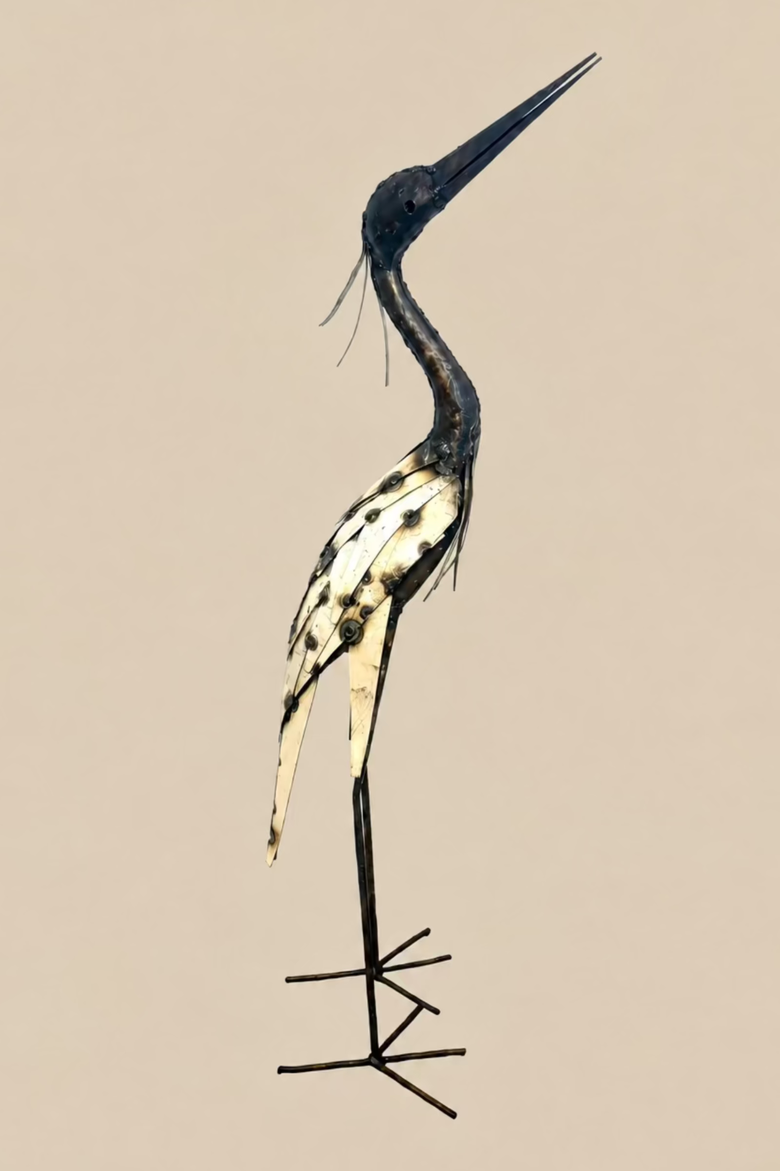Large Heron metal sculpture with a long dark neck, cream wing panels and slender legs, side view.