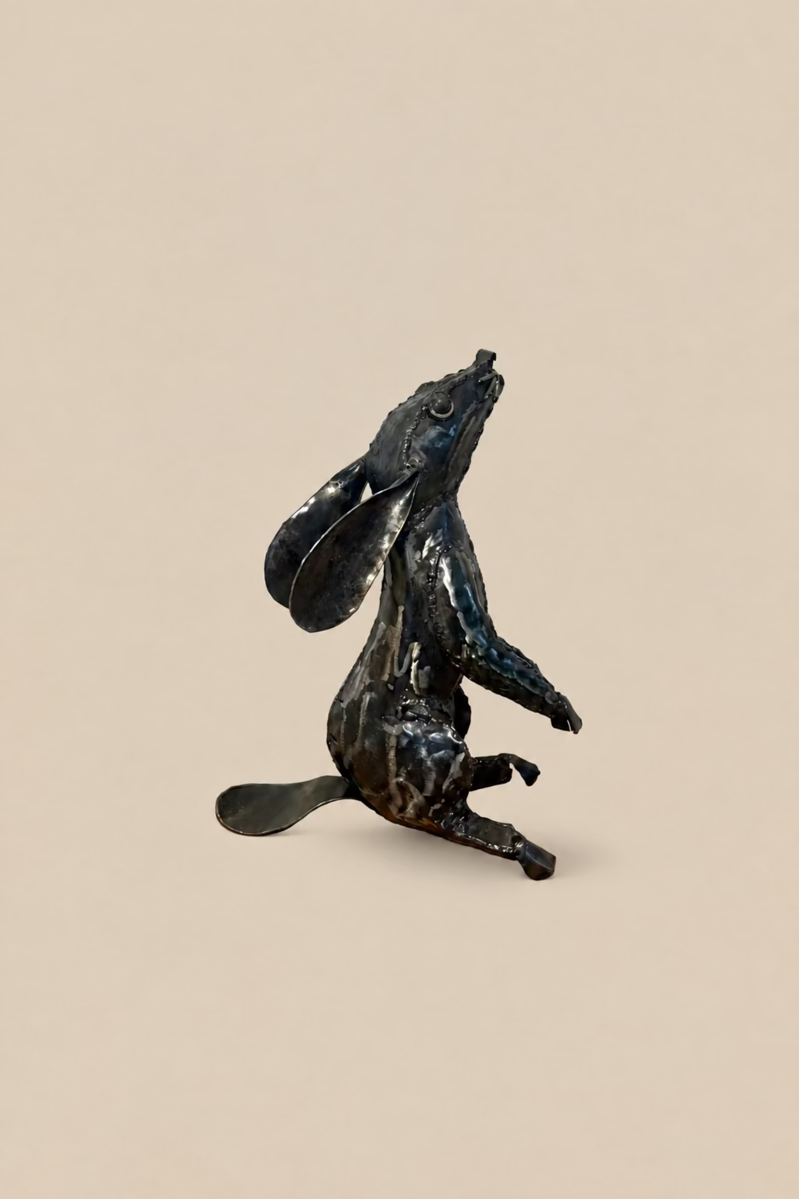 Dark metal Moon Gazing Hare with its head tilted upwards and long ears laid back, viewed from the opposite side.