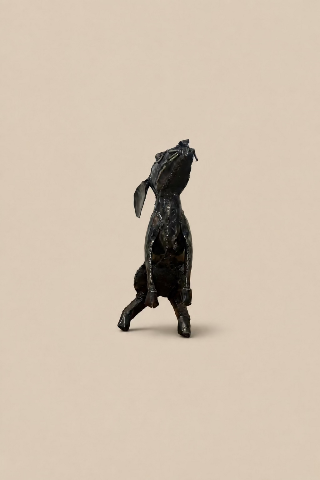 Dark metal Moon Gazing Hare with its head tilted upwards and long ears laid back, viewed from the rear.