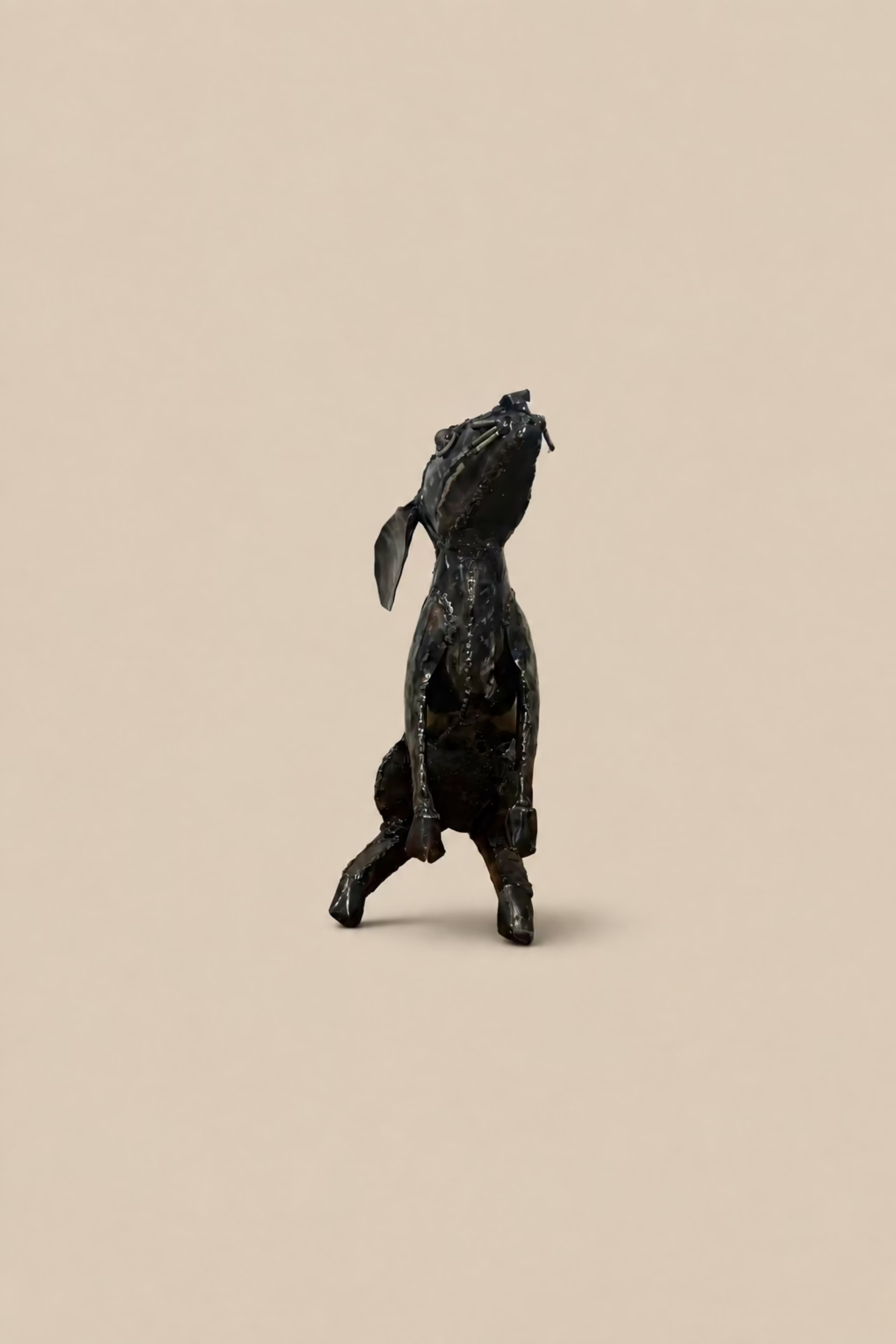Dark metal Moon Gazing Hare with its head tilted upwards and long ears laid back, viewed from the rear.