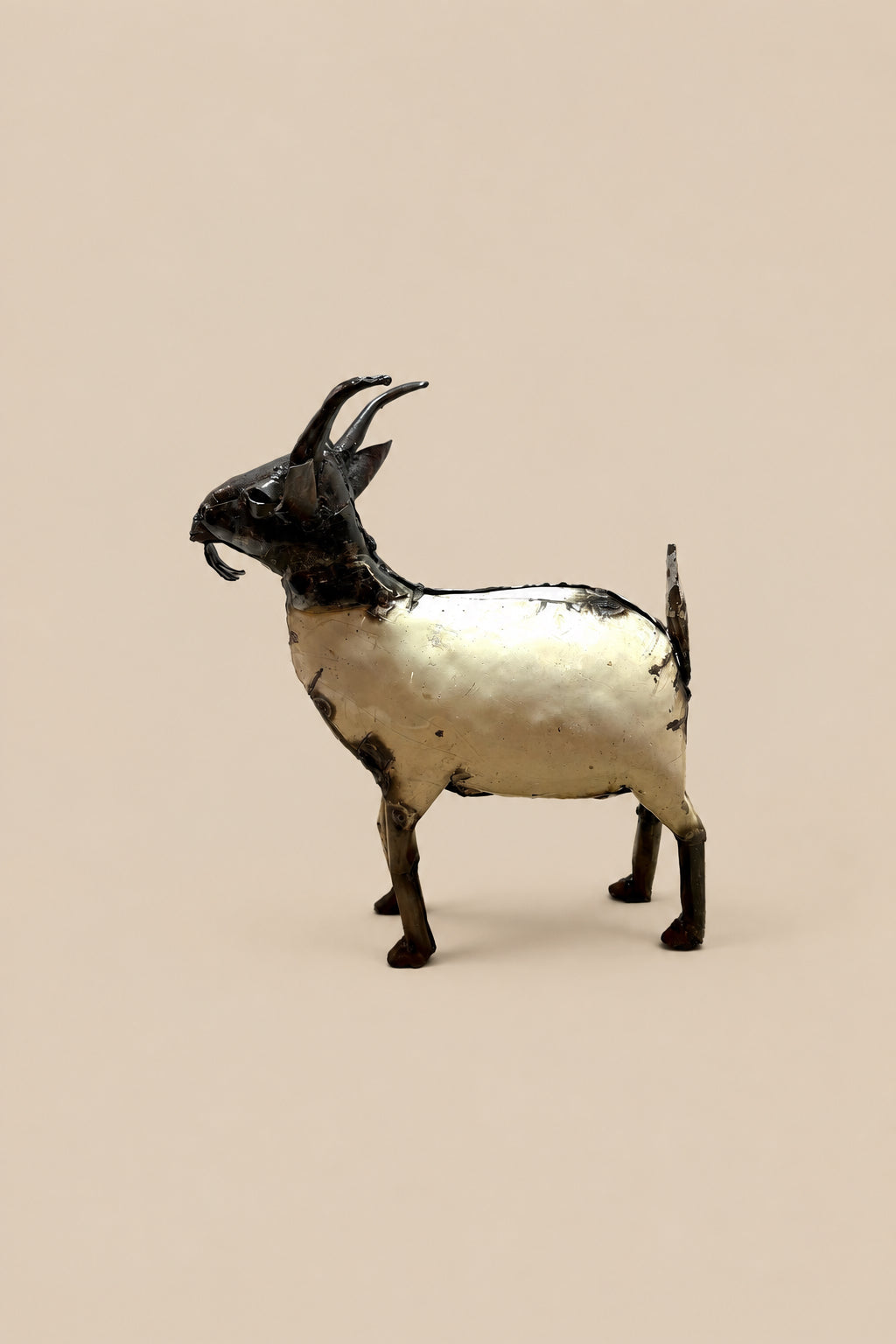 Cream-and-black recycled-metal goat with curved horns, in side profile.