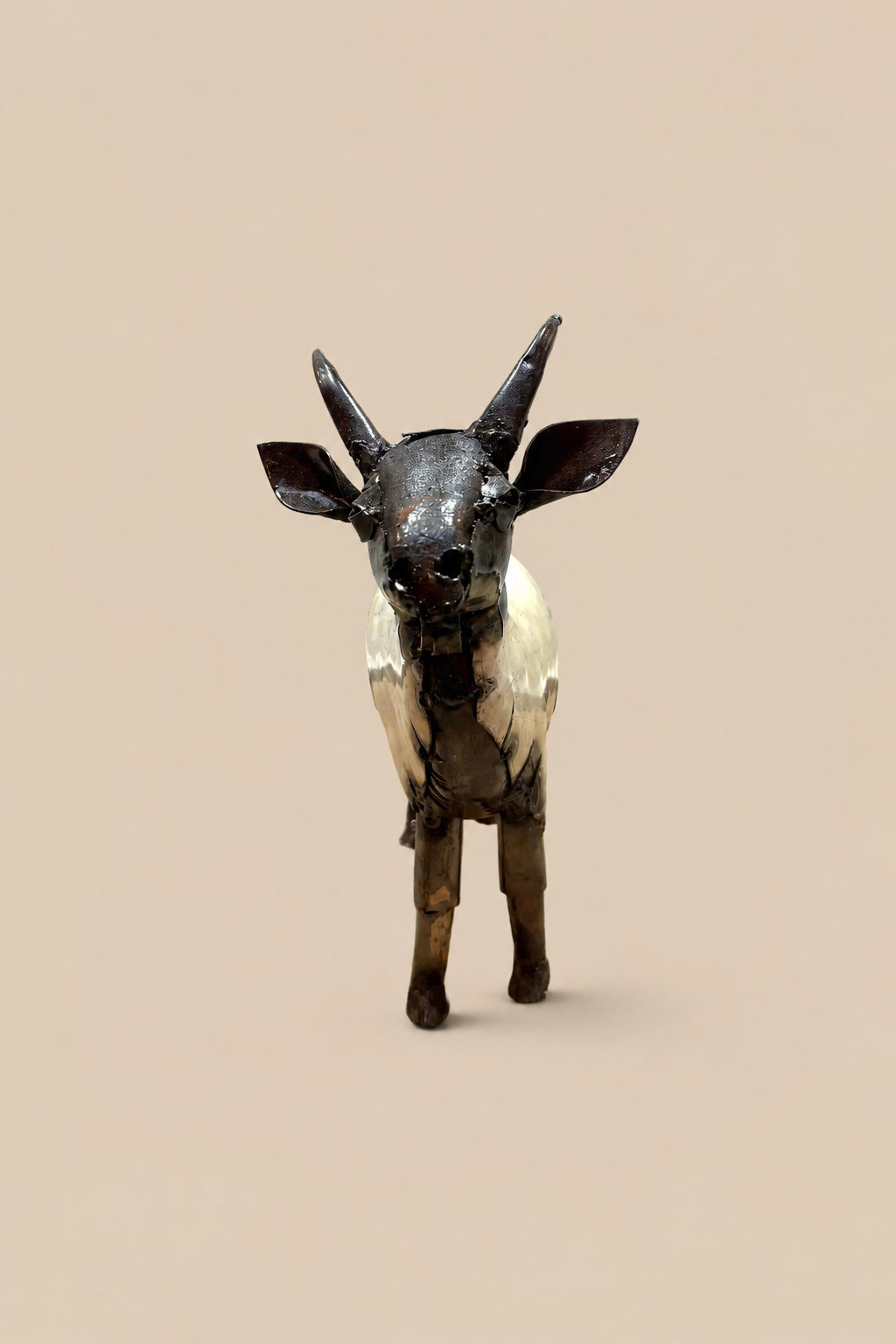Cream-and-black recycled-metal goat with curved horns, viewed from the front.