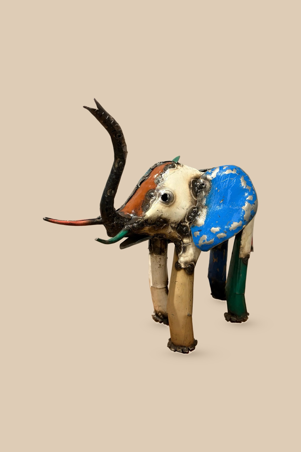 Medium Elephant sculpture in colourful reclaimed metal with a raised trunk, with cream and blue panels, viewed at an angle.