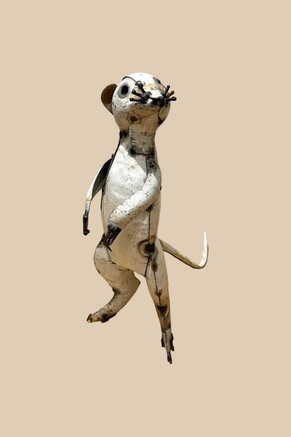 Pale recycled-metal meerkat standing upright with its forepaws raised, viewed from the front at an angle.