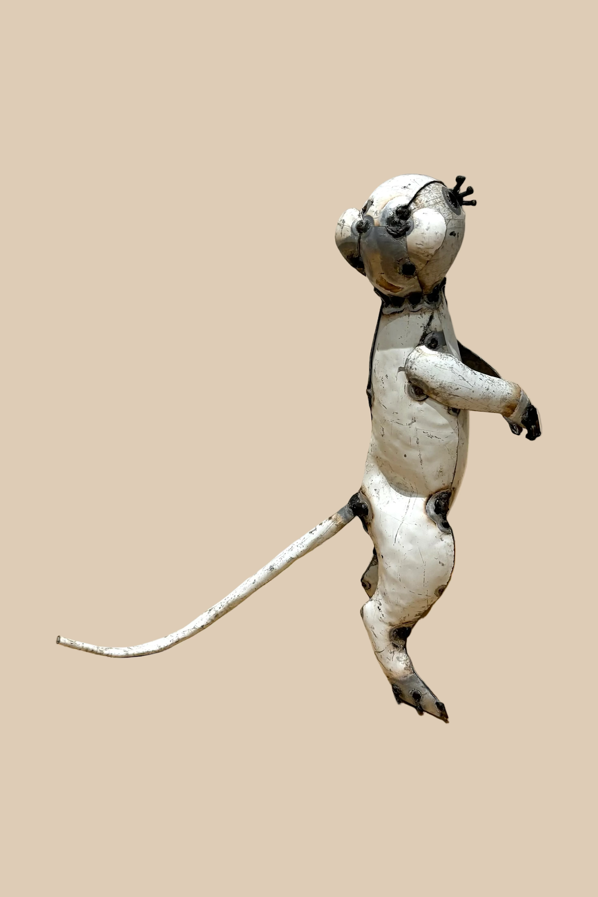 Pale recycled-metal meerkat standing upright with its forepaws raised, viewed from the opposite side.