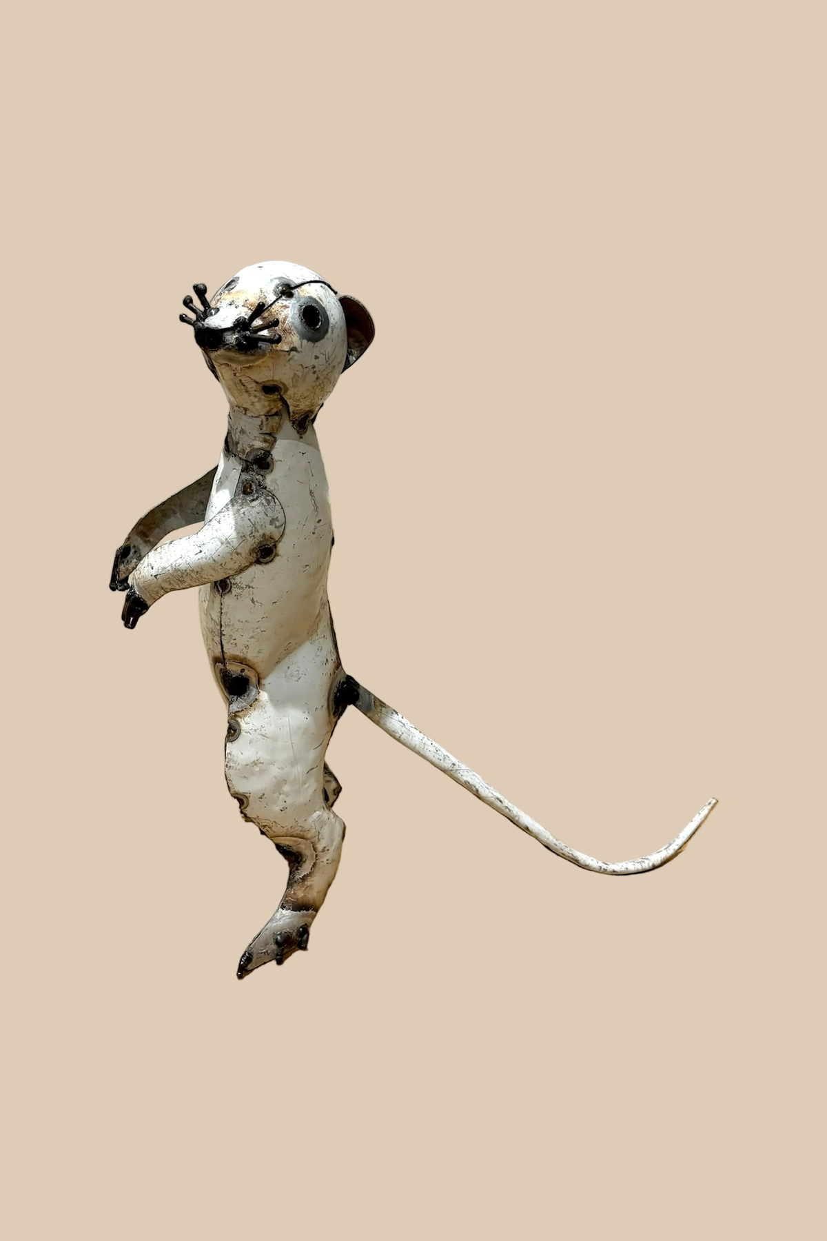 Pale recycled-metal meerkat standing upright with its forepaws raised, in profile with its long tail visible.