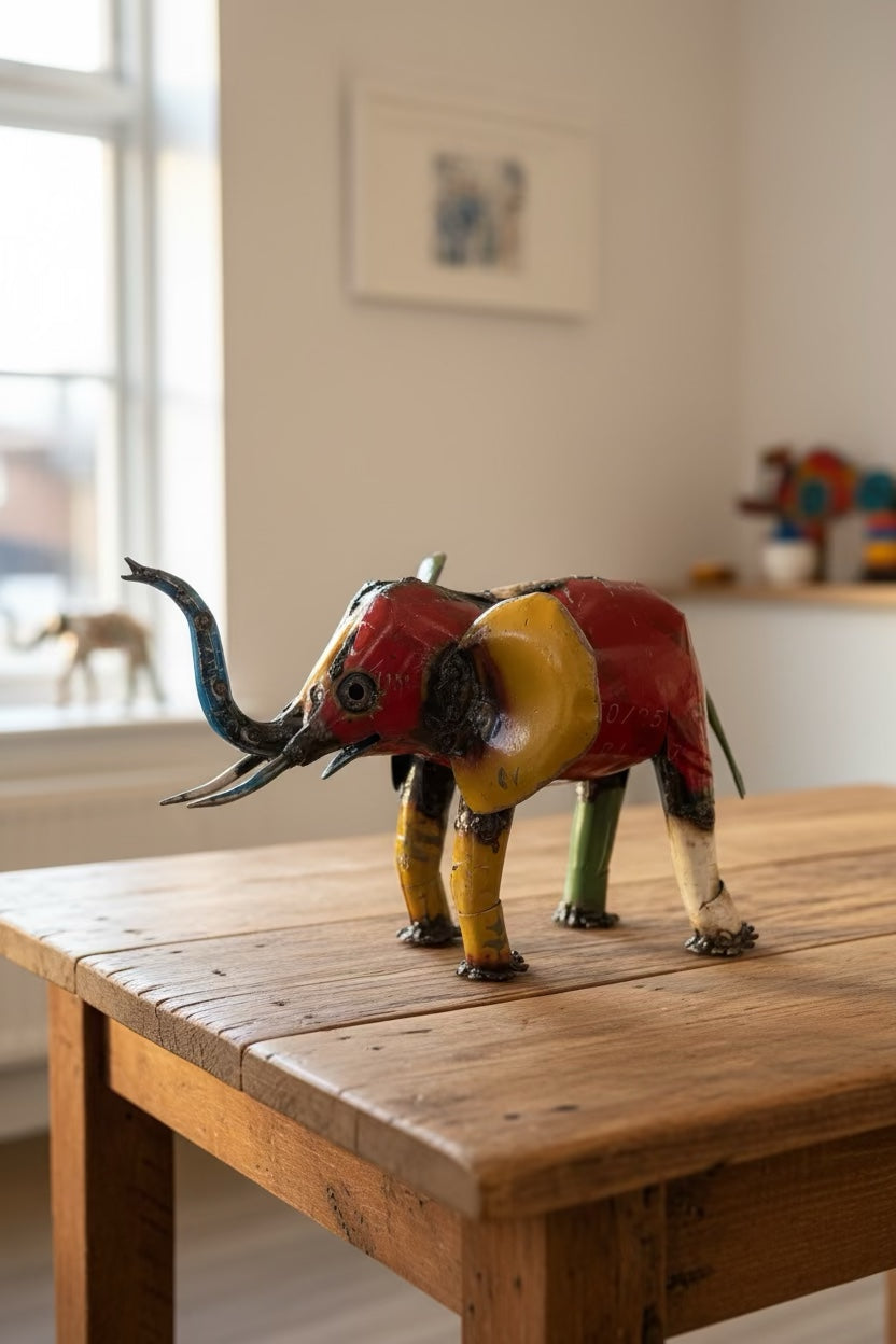 Small recycled metal elephant sculpture displayed on a wooden table indoors