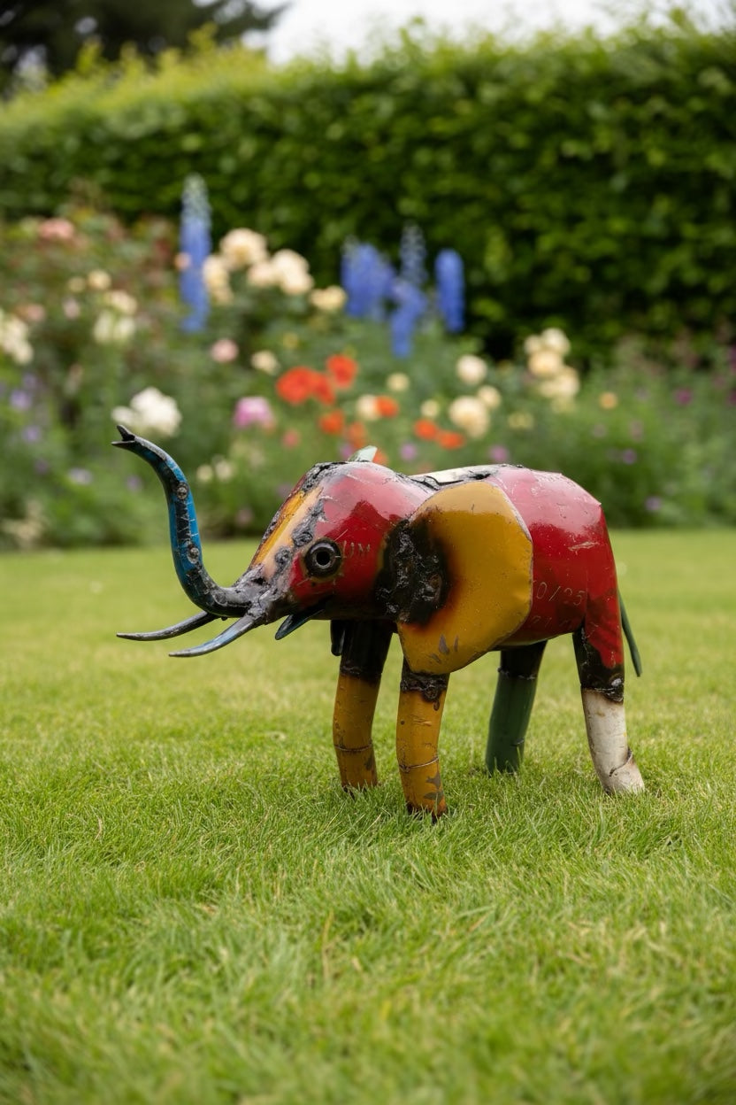Small recycled metal elephant sculpture standing on a lawn