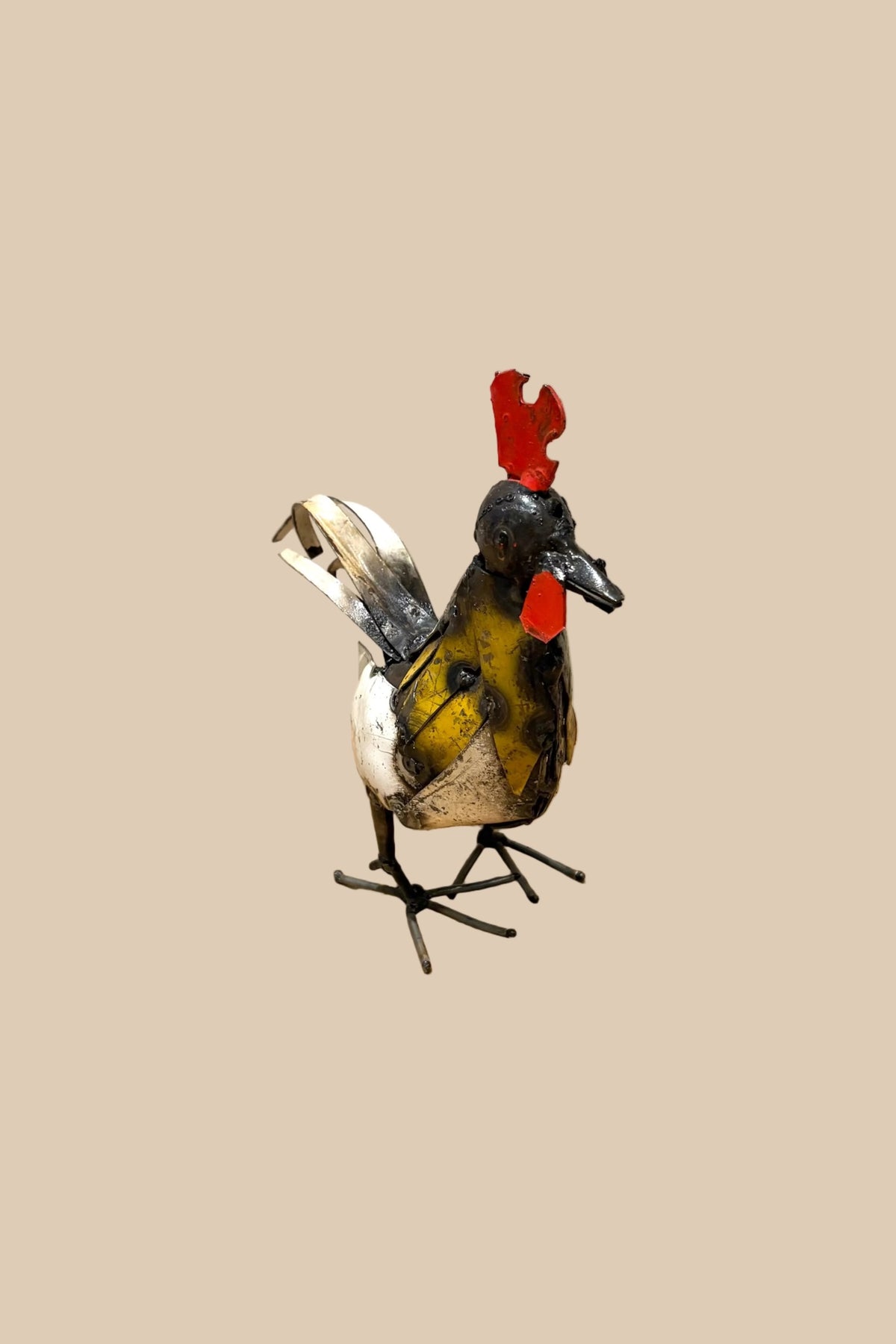 Small Cockerel metal sculpture with a red comb, yellow chest and pale tail feathers, viewed at an angle.