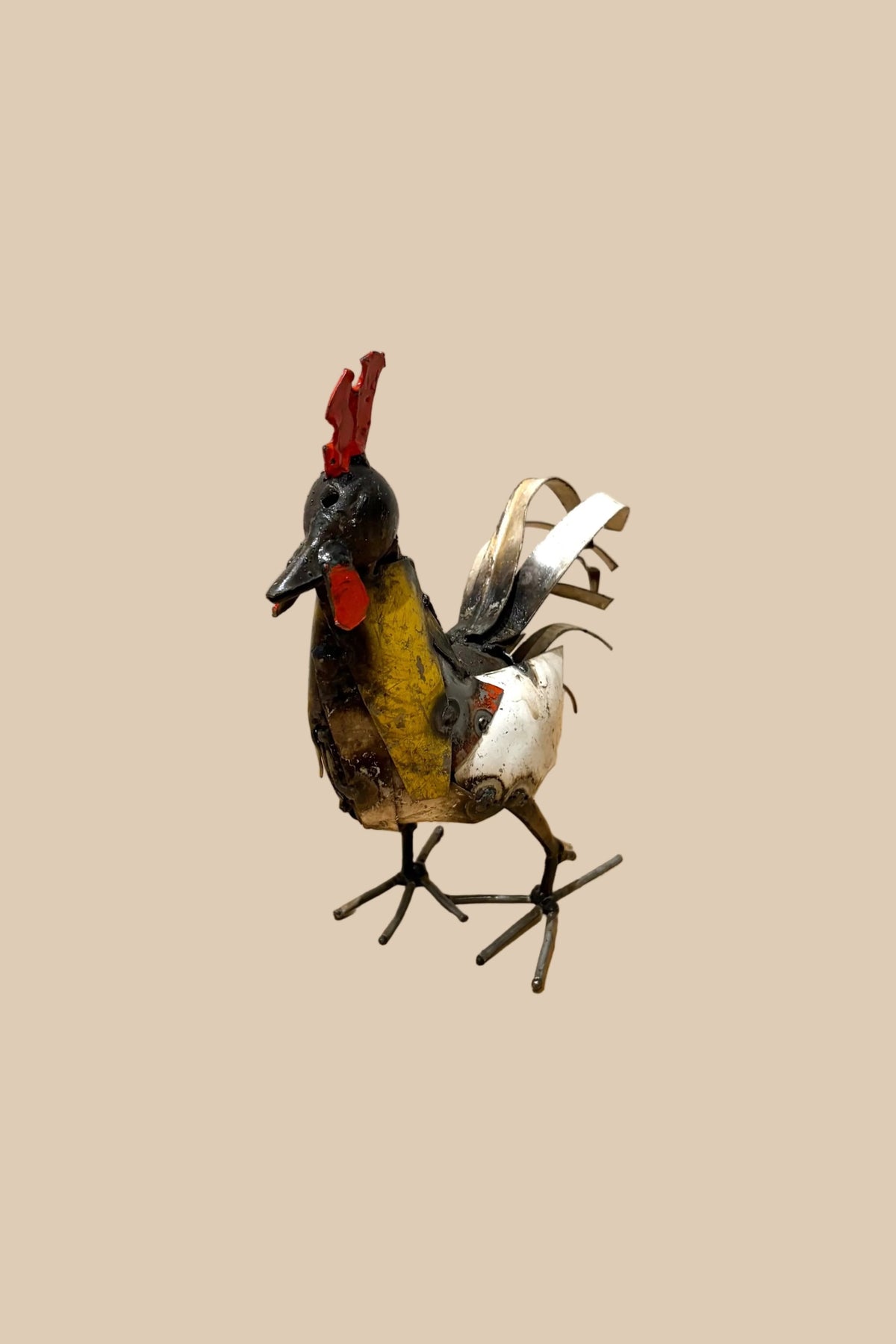 Small Cockerel metal sculpture with a red comb, yellow chest and pale tail feathers, viewed from the opposite side.